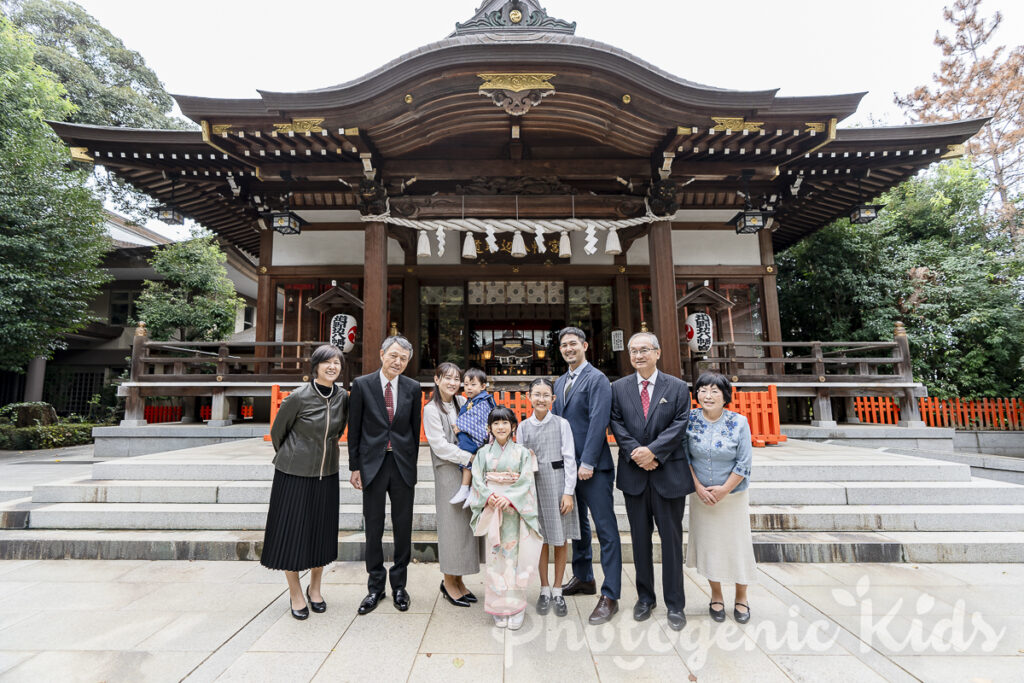 神社の本殿を背景にした七五三家族写真