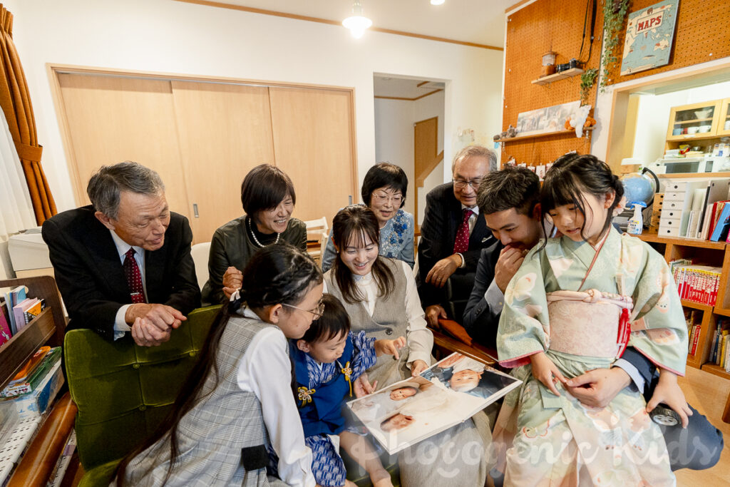 家族が自宅で写真集を一緒に見ている様子