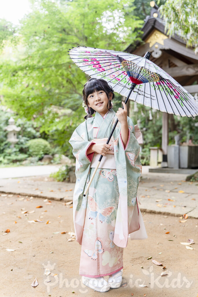 七五三の着物を着た7歳の女の子が神社の境内で微笑む姿