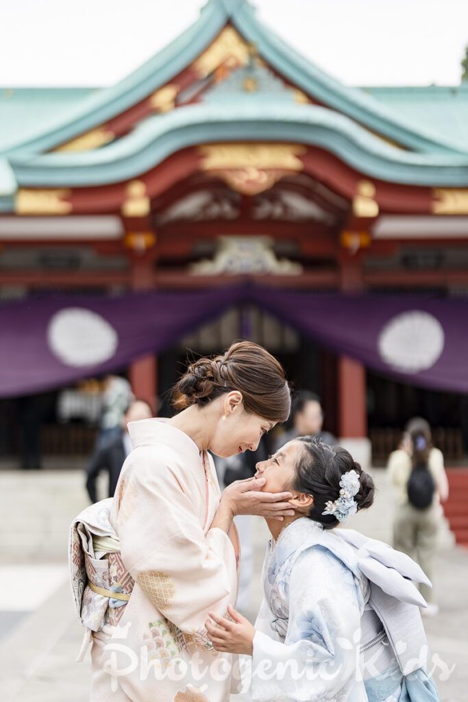 日枝神社本殿前で母が娘の頬に手を添える親子写真