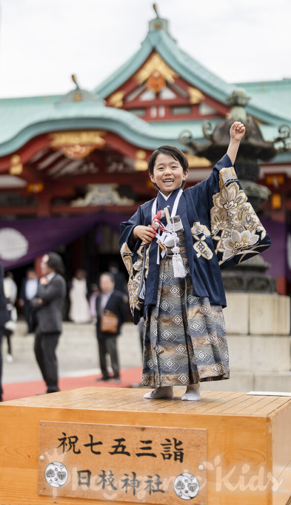 日枝神社でウルトラマンを手に碁盤に立つ七五三の男の子