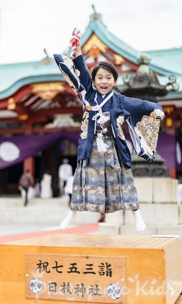 日枝神社でウルトラマンのポーズでジャンプする七五三男の子